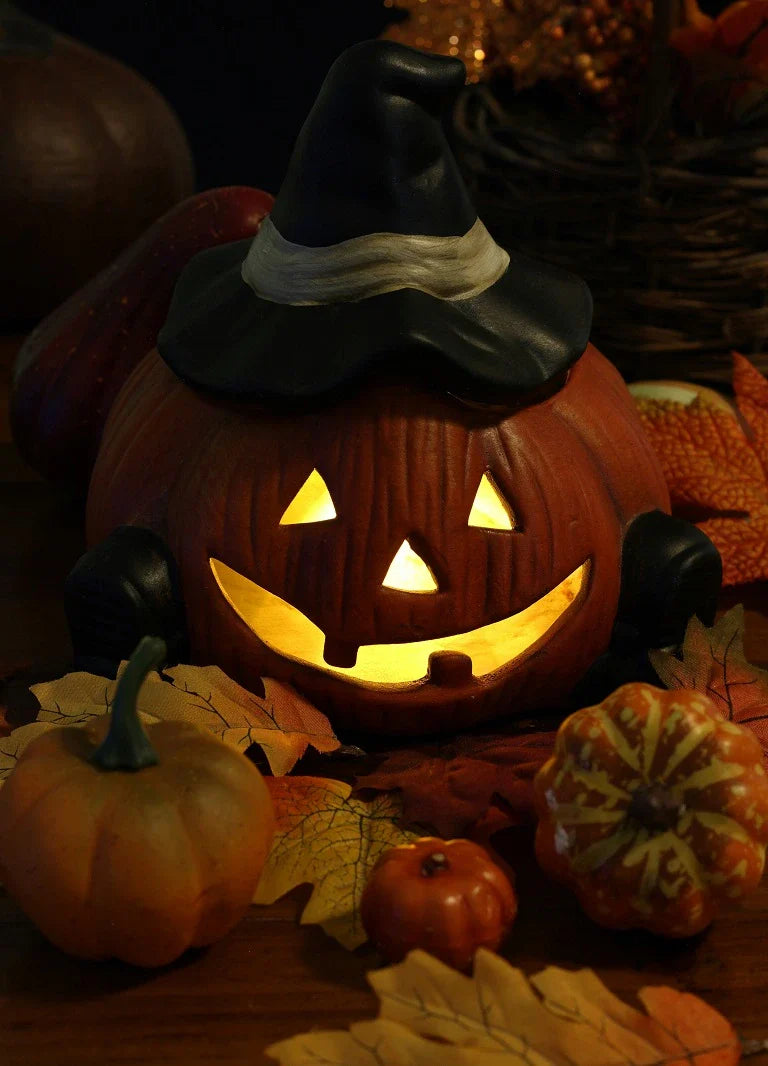 Glowing jack-o’-lantern pumpkin with a witch hat, surrounded by small pumpkins and autumn leaves on a wooden table, creating a festive Halloween scene.