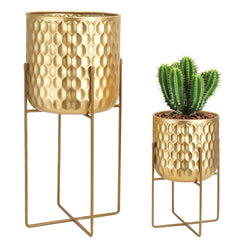 Two gold honeycomb-patterned planters with stands on a white background