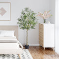 Modern bedroom with a bed, dresser, and decorative artificial olive tree plant.