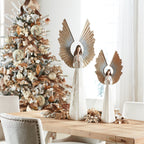 Decorative angel statues on a table with a Christmas tree in the background