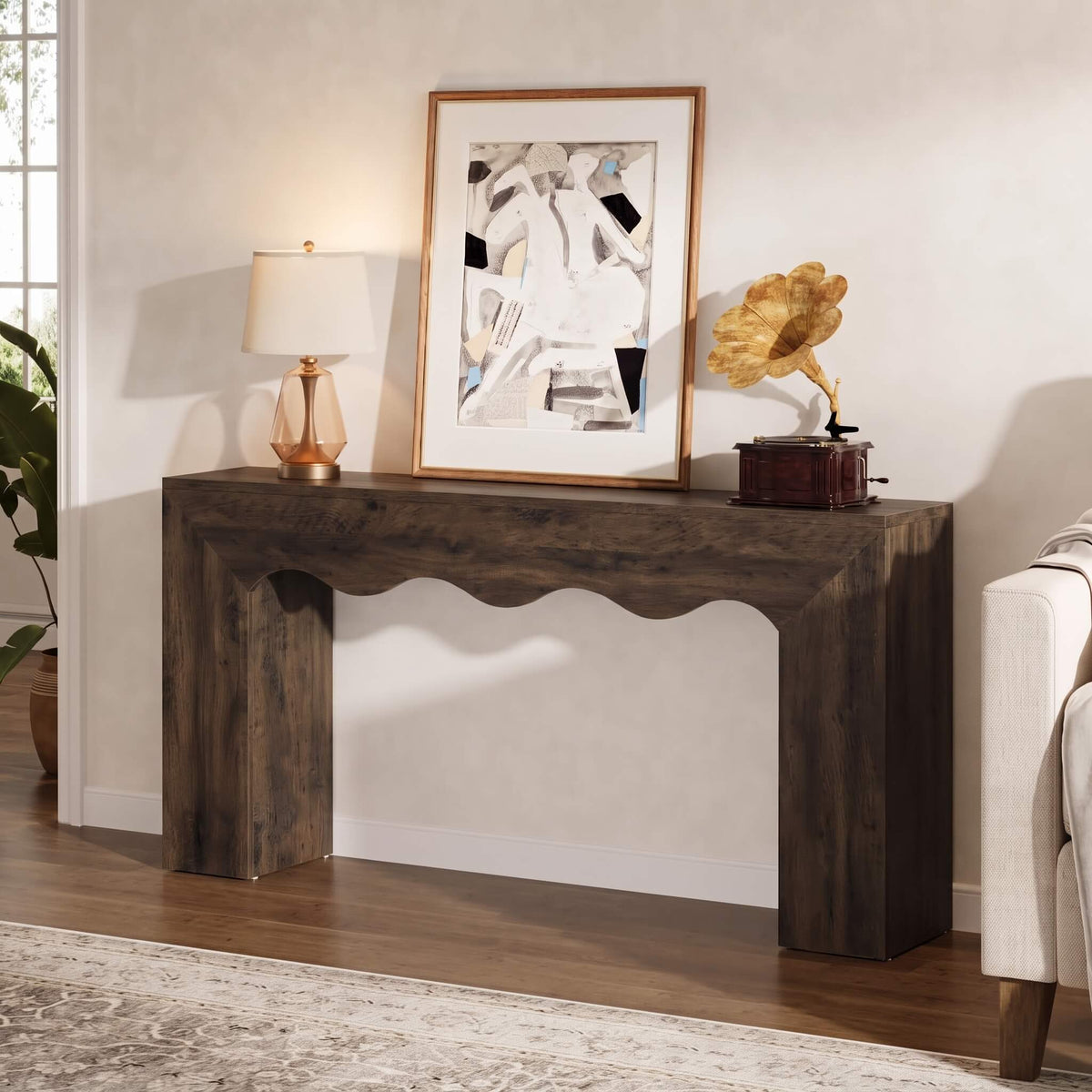 A dark brown rustic console table styled in a living room setting with a lamp, framed art, a gramophone, and a chair visible.