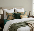 Neatly made bed with decorative pillows and a green throw blanket in a bedroom setting.