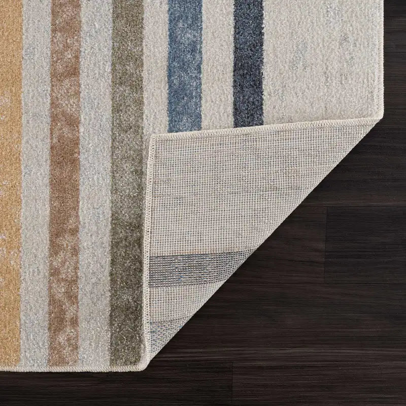 Striped Giza Contemporary Washable Multicolor Rainbow Rug with brown, gray, and blue colors on a wooden floor.