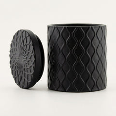 Forbidden Masculine Scent — Matte Black Textured Ceramic Candle with Lid, shown on a clean white background. The container features a raised wavy diamond pattern, and the lid displays a matching embossed floral or sunburst design.