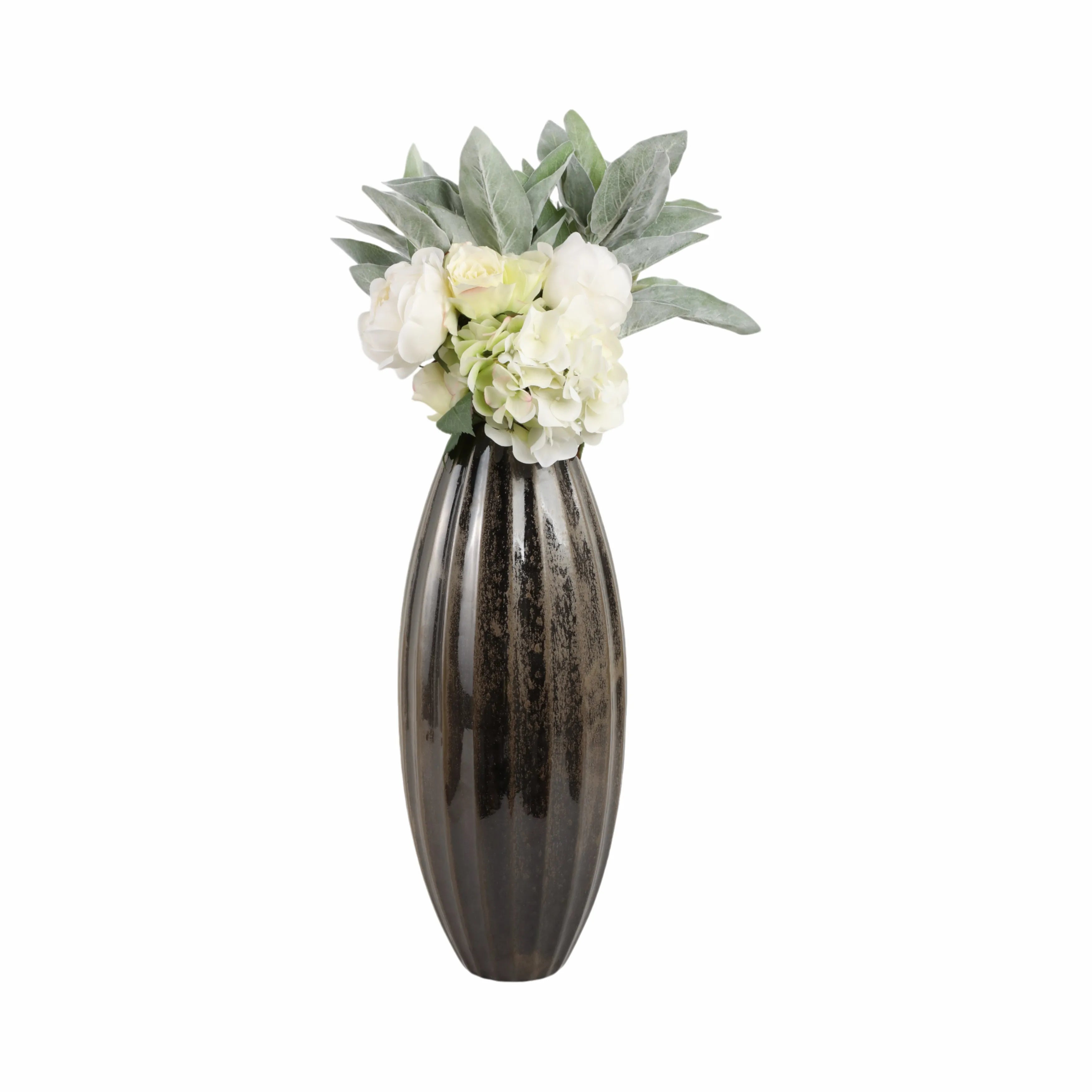 A tall, ribbed dark brown ceramic vase filled with white and pale green artificial flowers and leaves, set against a plain white background.