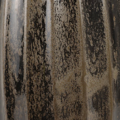 Close-up of a glossy ceramic surface with vertical fluting and a brushed pattern of black, beige, and gray glaze.