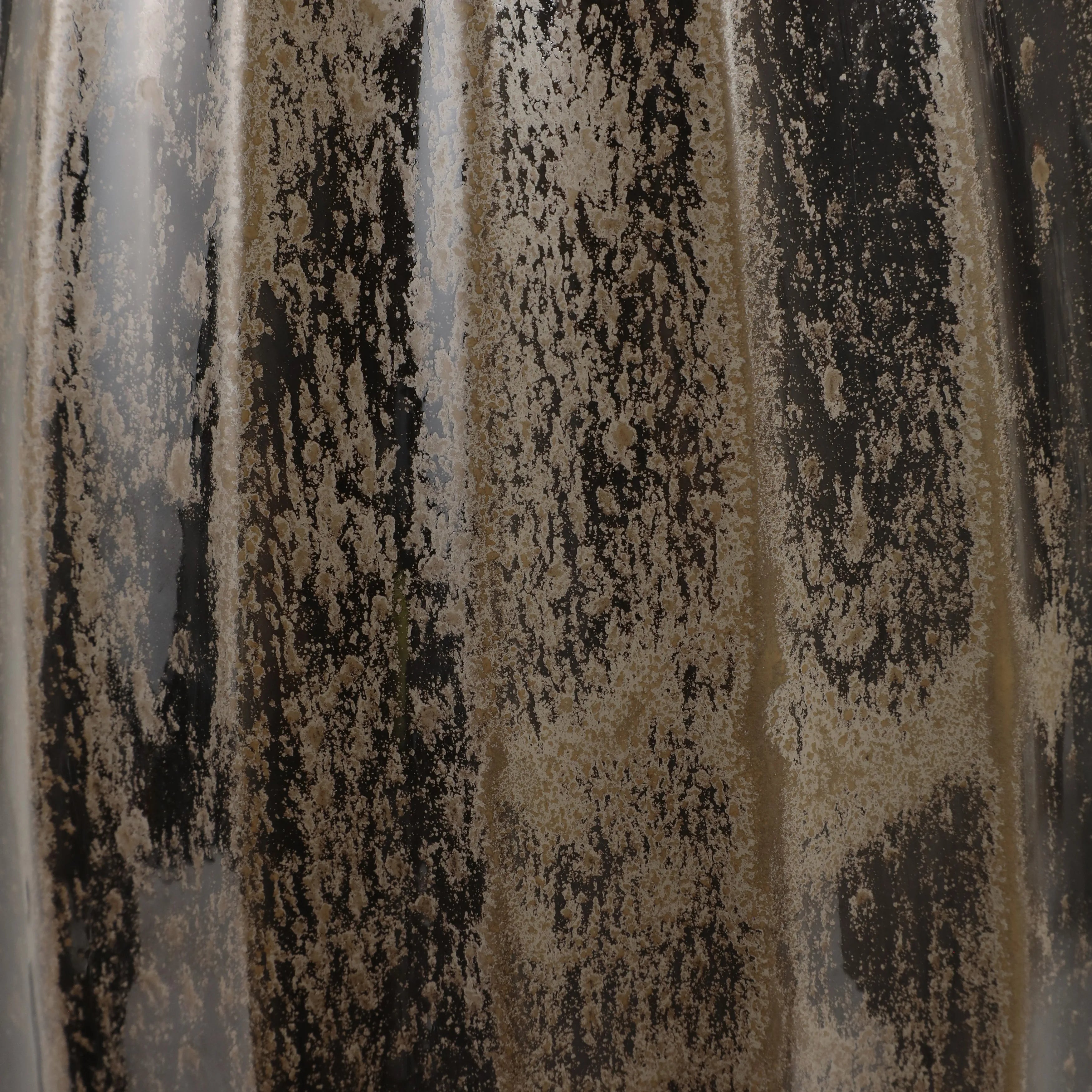 Close-up of a glossy ceramic surface with vertical fluting and a brushed pattern of black, beige, and gray glaze.