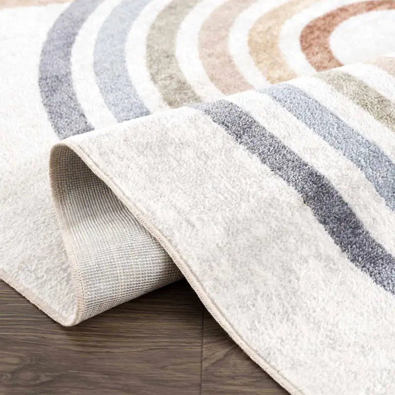 Roll of striped Giza Contemporary Washable Multicolor Rainbow Rug showing it's neutral colors on a wooden floor