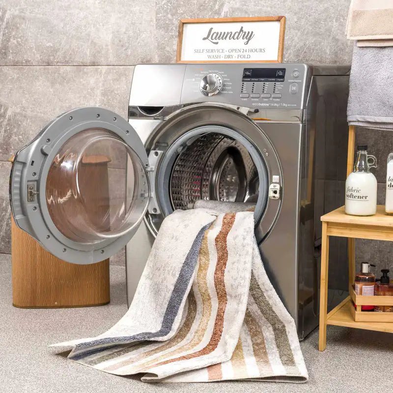 Laundry room with open dryer door and the striped Giza Contemporary Washable Multicolor Rainbow Rug, 'Laundry' sign on wall.