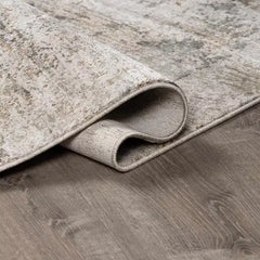 Rolled-up beige  Meral Thick Luxe Boutique Rug on a wooden floor