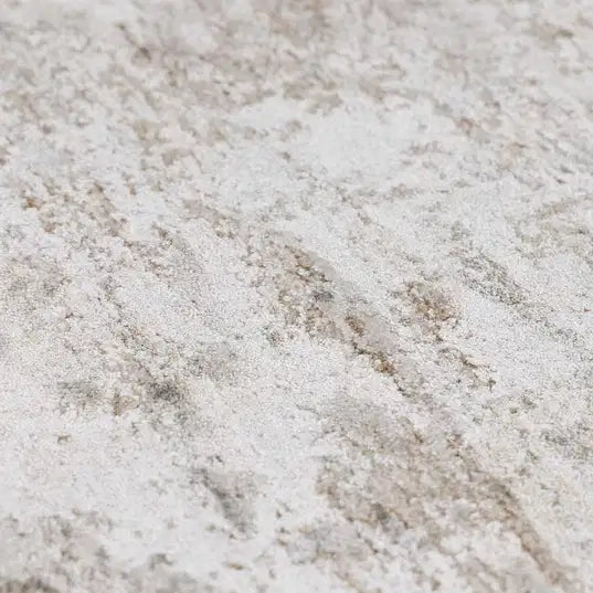 A close-up texture shot of a  Meral Thick Luxe Boutique Rug distressed area rug with a mottled pattern of off-white, beige, and light gray.