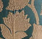 Close-up of a textured throw pillow's gold leaves on a teal background