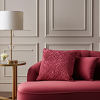 Red berry sofa with textured cushions in a room with panelled walls and a lamp.