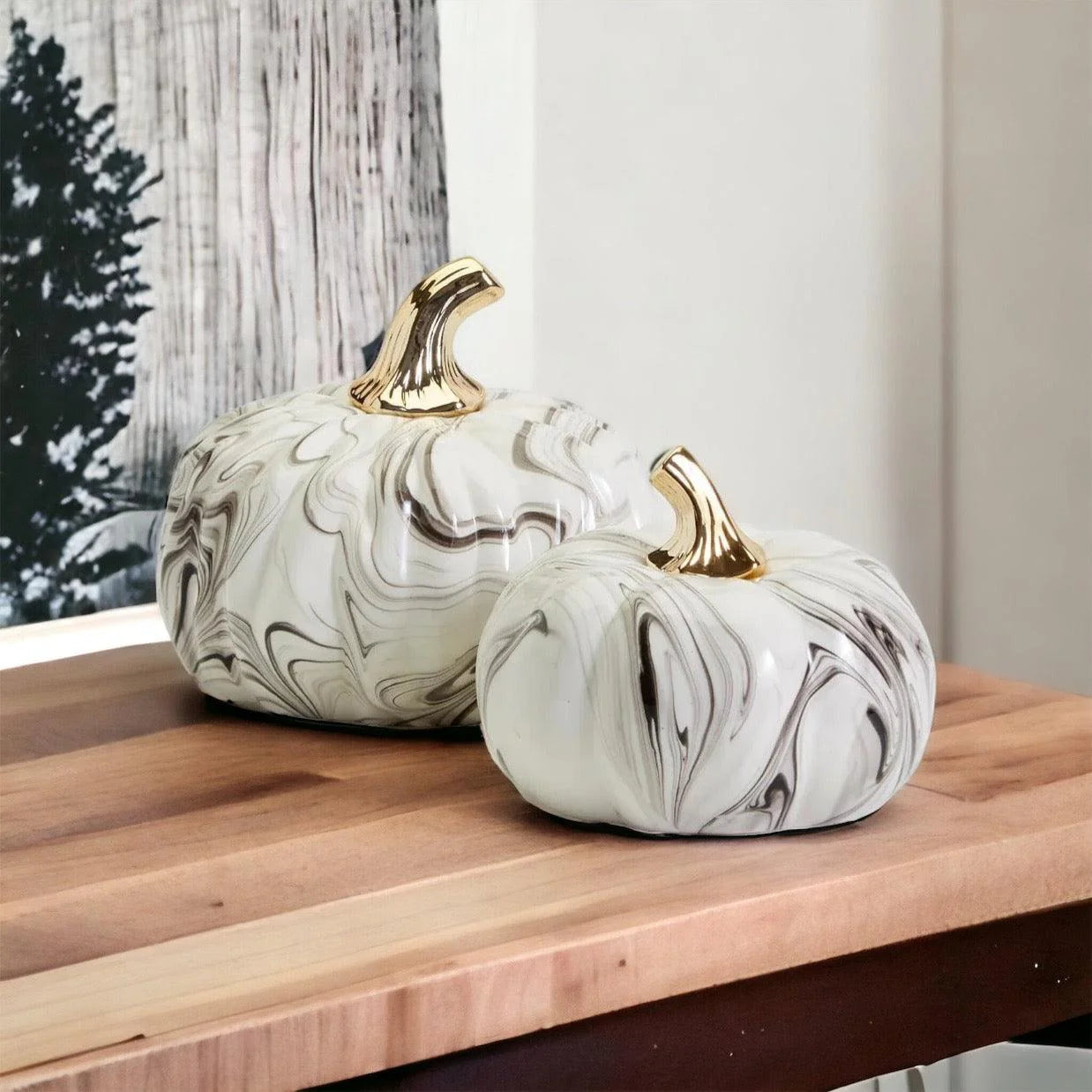 Two marble-patterned pumpkins with gold stems on a wooden surface.