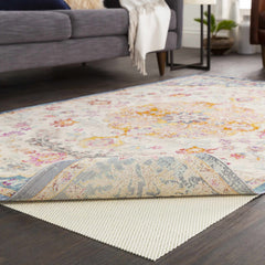 Floral patterned rug and rug pad on a wooden floor with a gray sofa in the background