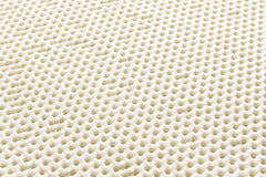 Close-up of a textured beige rug pad with dotted patterns