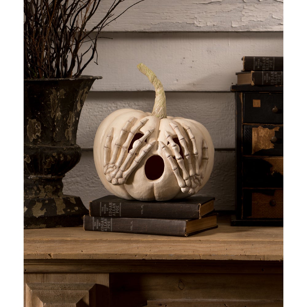 Decorative pumpkin with skeleton hands on a wooden surface