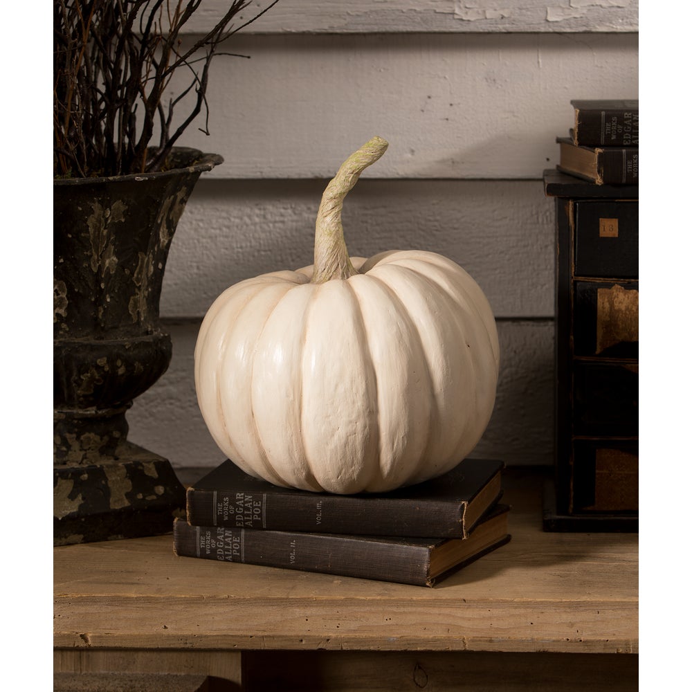 White pumpkin on stacked books with a decorative background