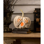 Decorative pumpkin with skeleton hands and glowing interior on a wooden surface