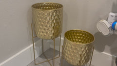 Customer reviewing the set of 2 gold metal honeycomb planters in a living room.