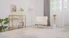 Video of a modern living room with one ivory and gold armchair, side shelf, neutral decor, and potted yellow flowers. The video shows a close-up of the armchair revealing its soft suede msterial and upholstered design.